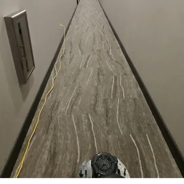 Long carpeted hallway being cleaned with a low-moisture carpet machine