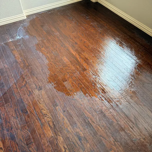 Dark hardwood floor halfway through cleaning, showing the difference