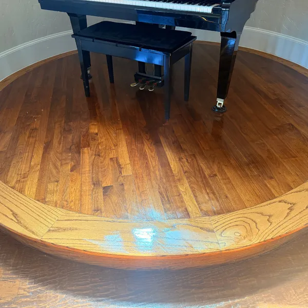Glossy hardwood floor around a piano after cleaning and buffing