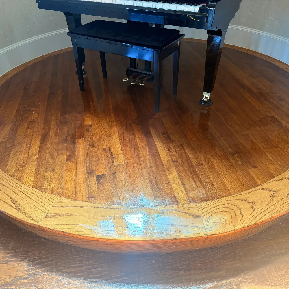 Glossy hardwood floor around a piano after cleaning and buffing