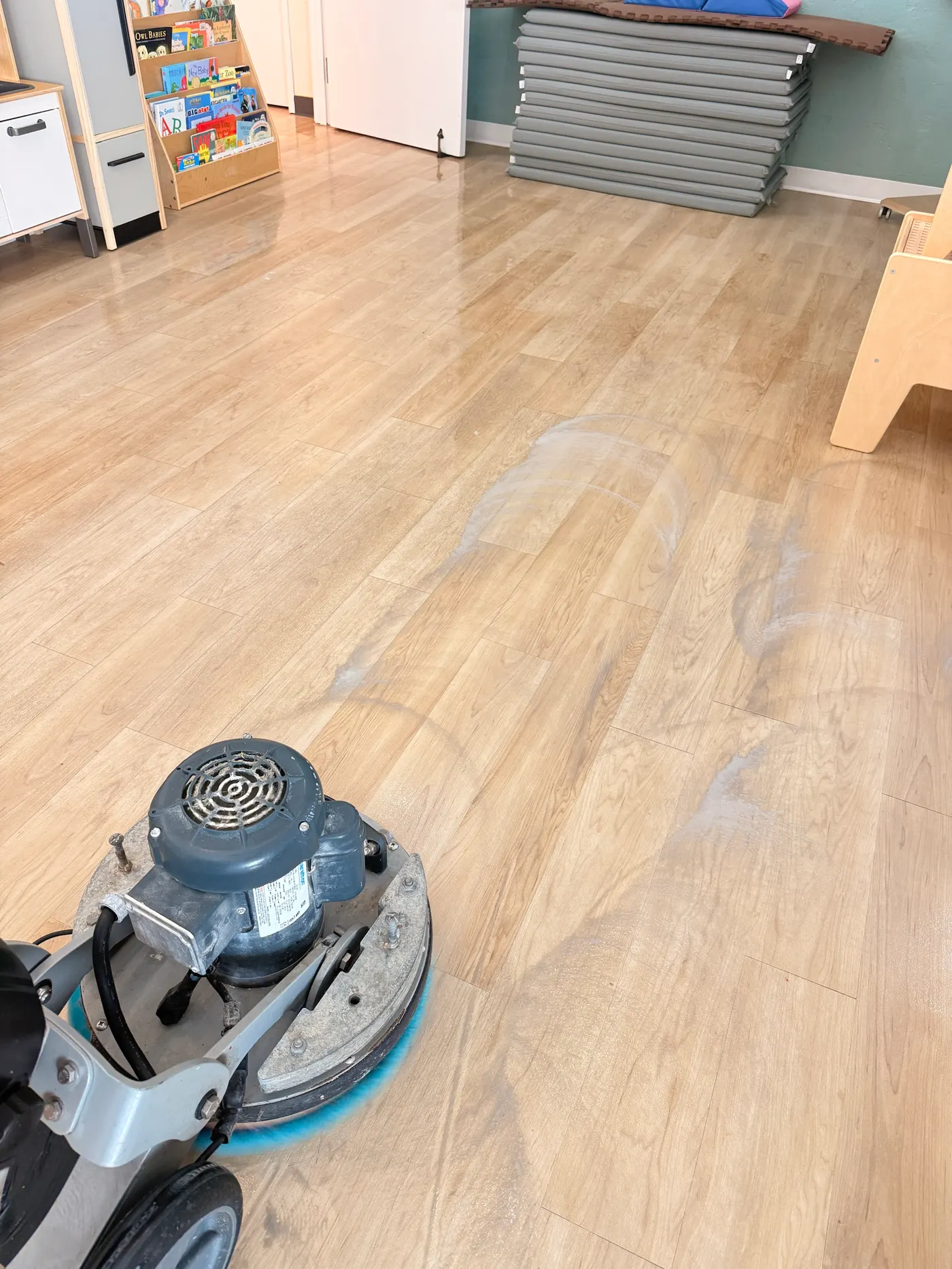 Floor machine scrubbing vinyl plank during daycare floor cleaning in Southlake, cleaned and uncleaned areas side by side