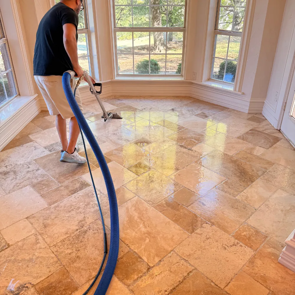 Hank's technician cleaning a glossy travertine floor in a sunlit breakfast room