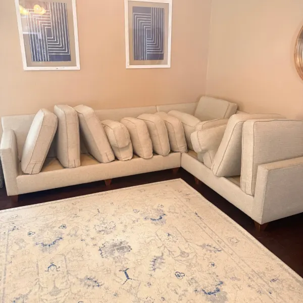 Beige sectional with cushions propped up to dry